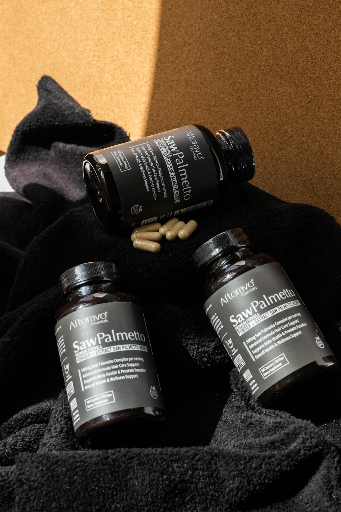Three Saw Palmetto supplement bottles with capsules on a textured black surface.